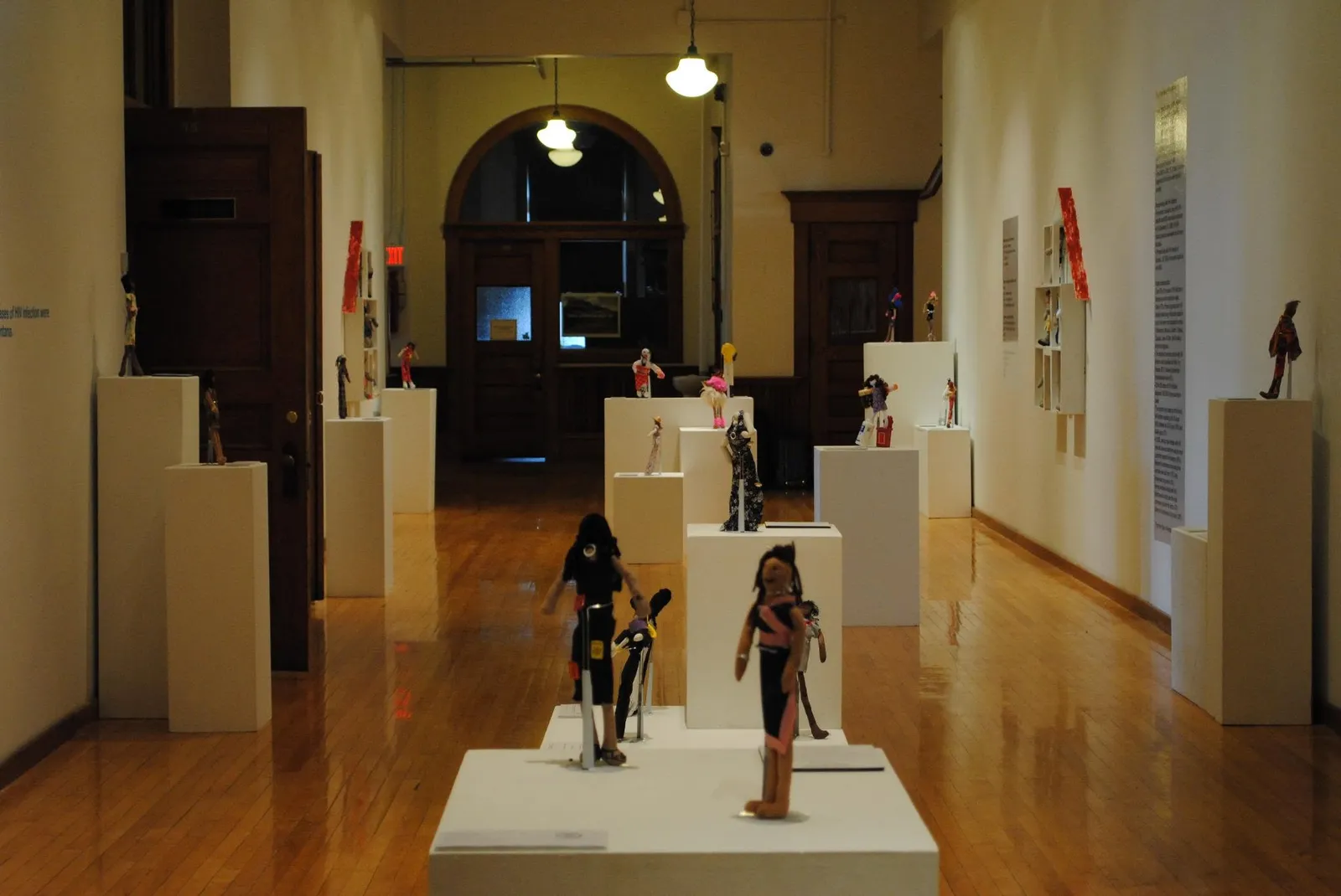 Handmade Stitches dolls displayed on white stands throughout an art exhibition
