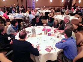 Participants gathered around a table of materials at a doll-making workshop
